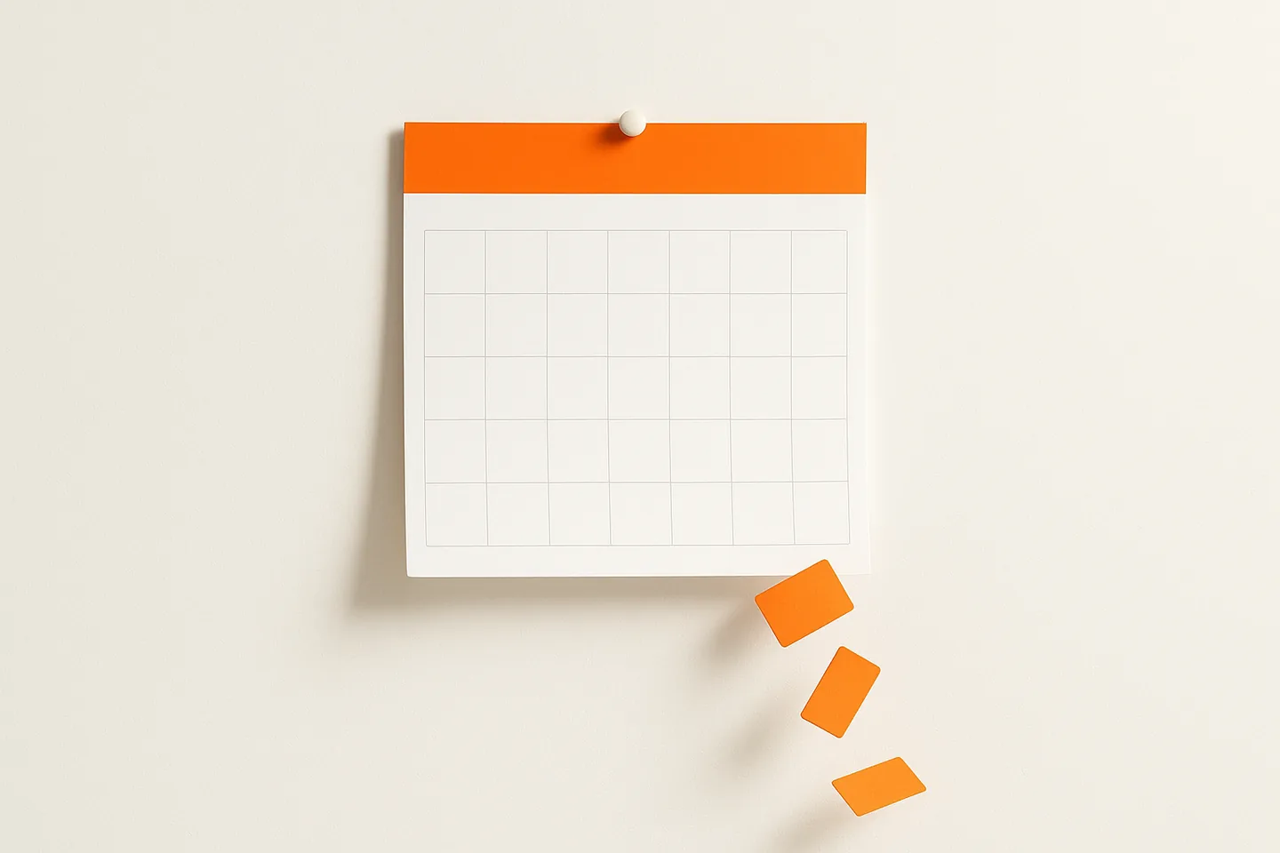 An orange wall calendar page on a white wall with a few small orange cards slipping off the bottom edge