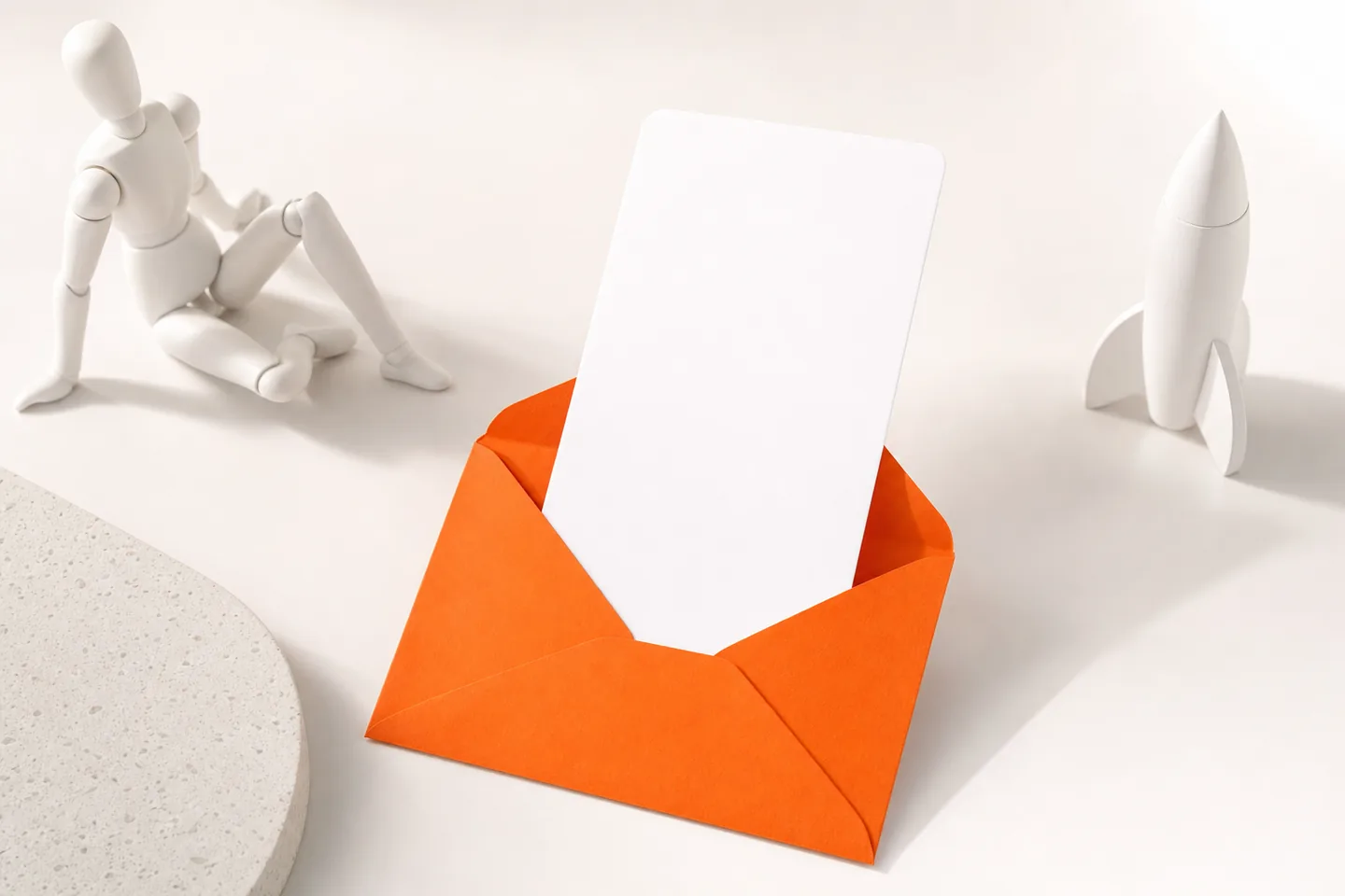 A single orange envelope on a white table with one tall card sliding out of it
